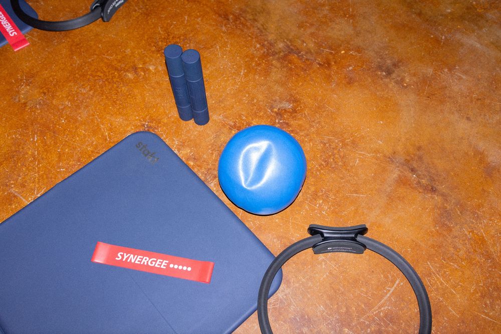Fitness equipment including blue exercise balls and resistance bands arranged on a wooden floor.
