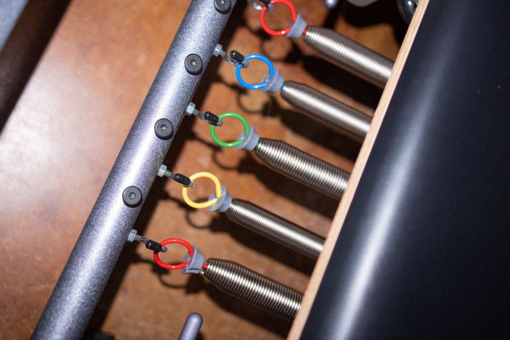 Detail shot of metal springs and adjustments on Pilates reformer machine.