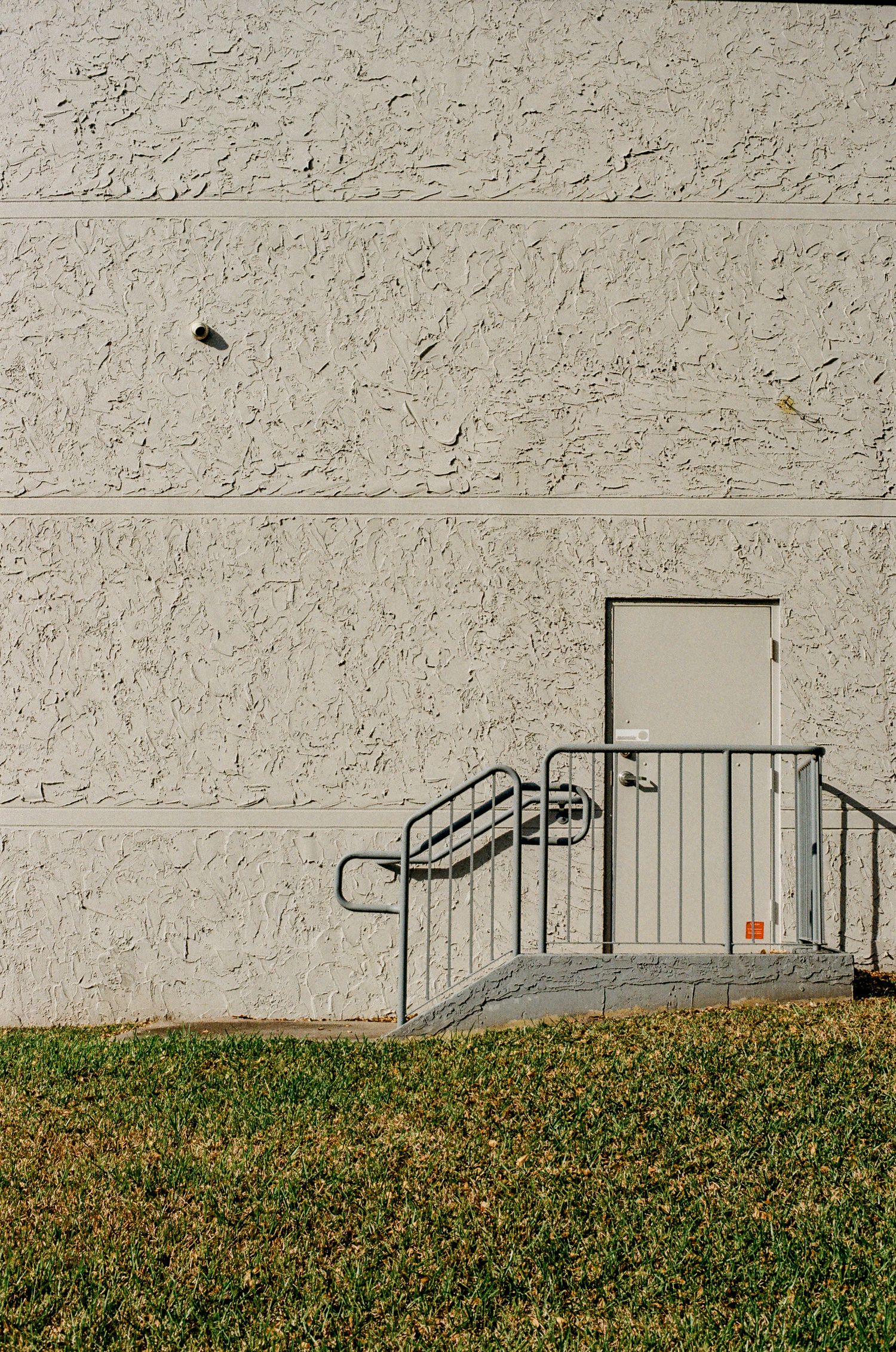 A couple in wedding attire shares an intimate moment on the ground against a concrete architectural backdrop.