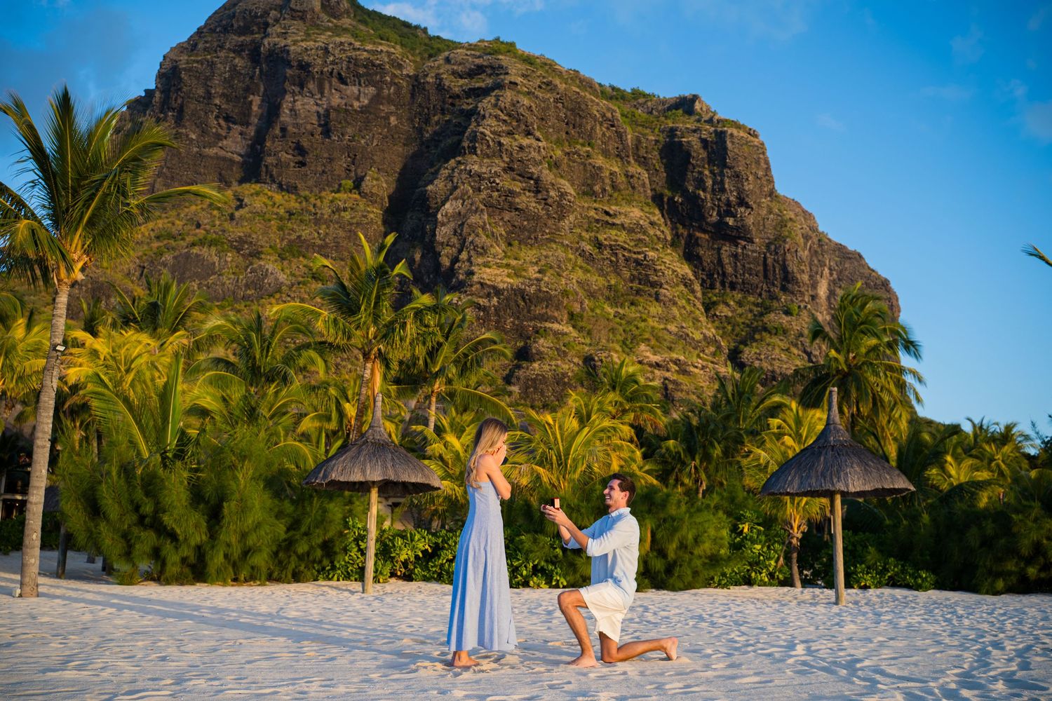 A proposal scene on a beach with dramatic mountain backdrop.