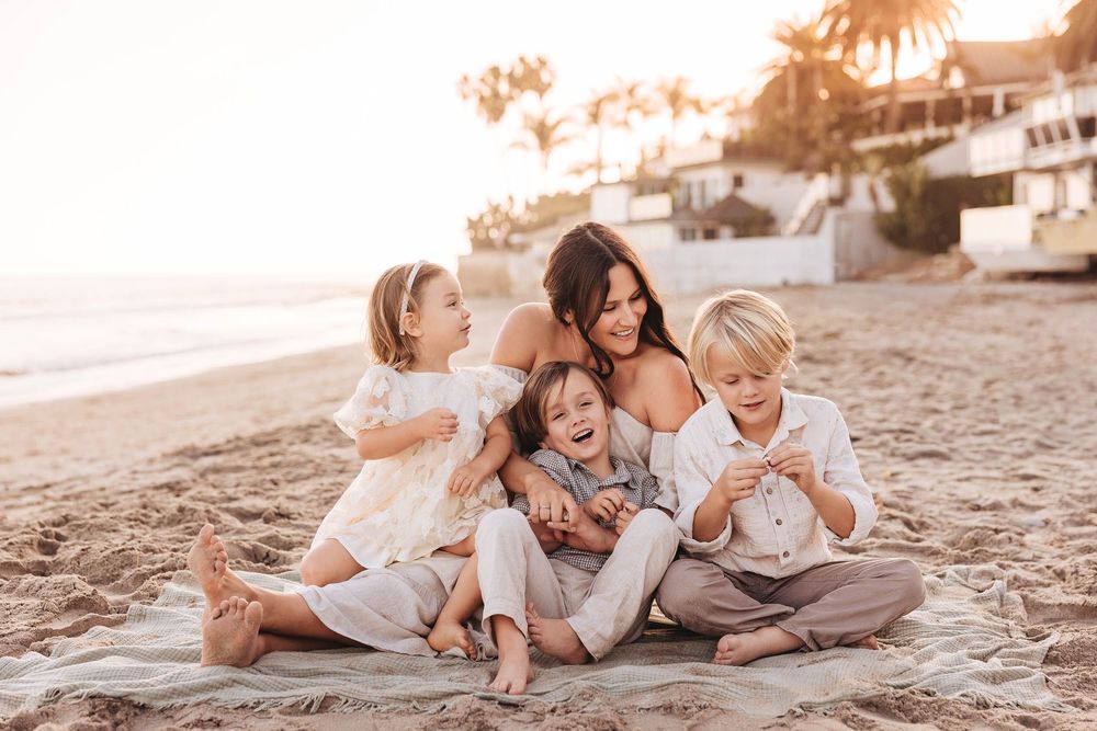 Family enjoying quality time together on a sandy beach during sunset.