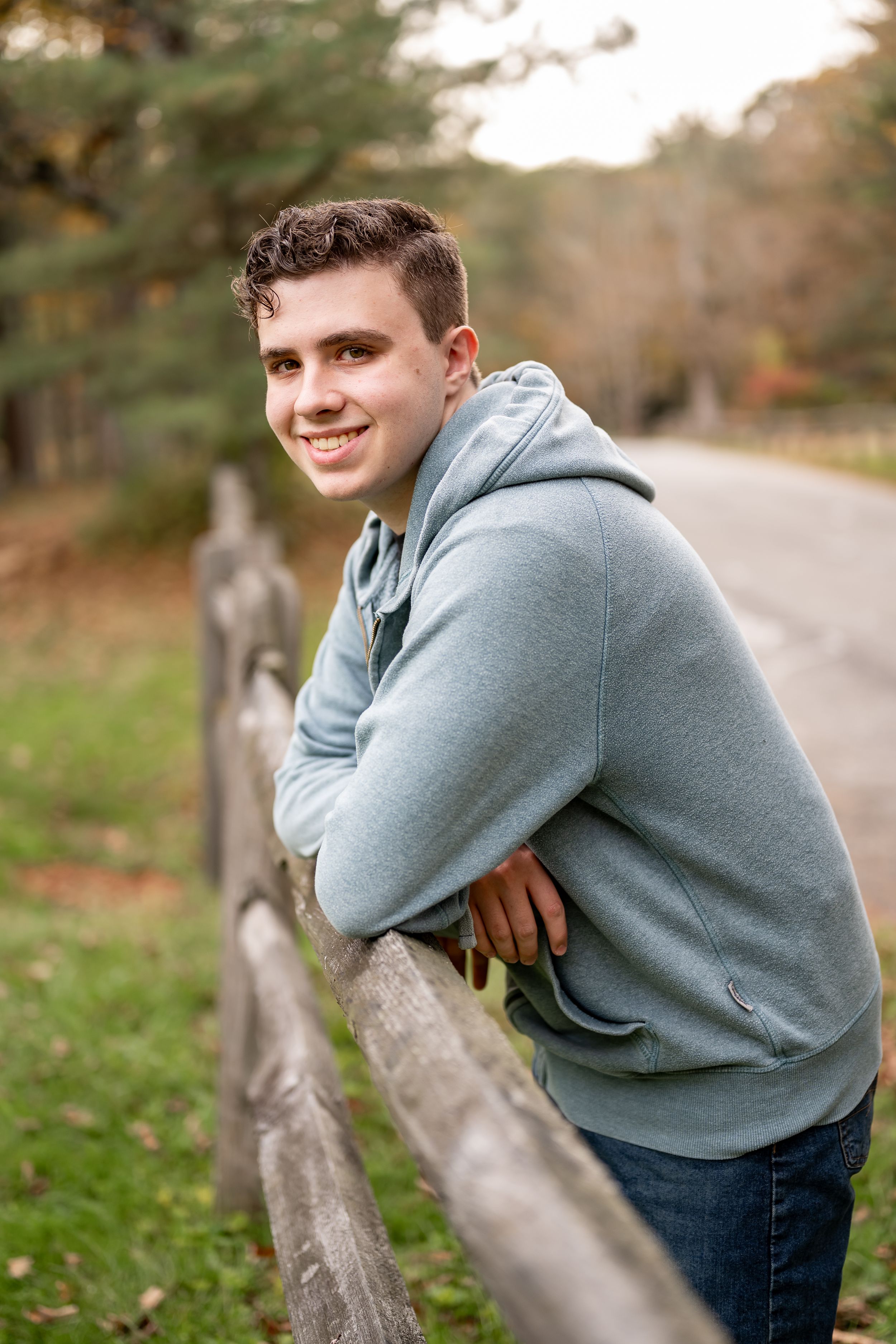A series of casual outdoor portraits showing someone in a gray hoodie leaning on a wooden fence in autumn.