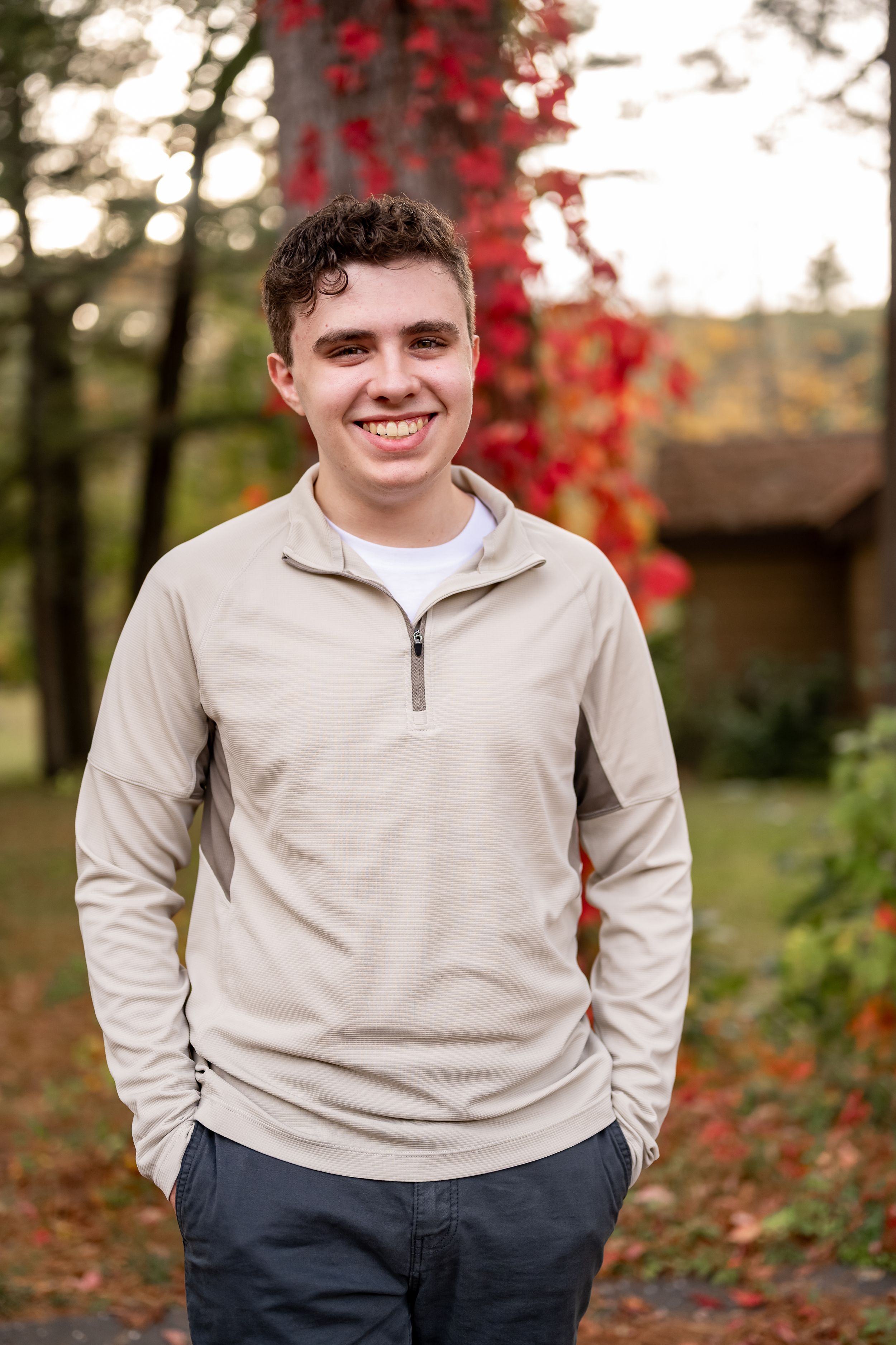 A series of outdoor portrait photos in autumn featuring someone wearing a beige quarter-zip sweater against red foliage.