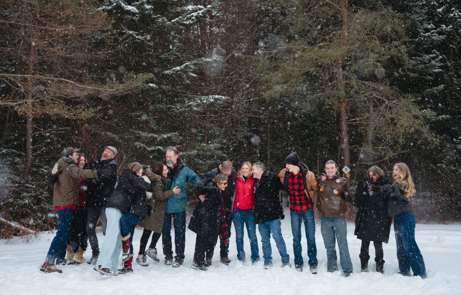 A group of people enjoying a snowy winter day in the forest while wearing warm winter clothing.