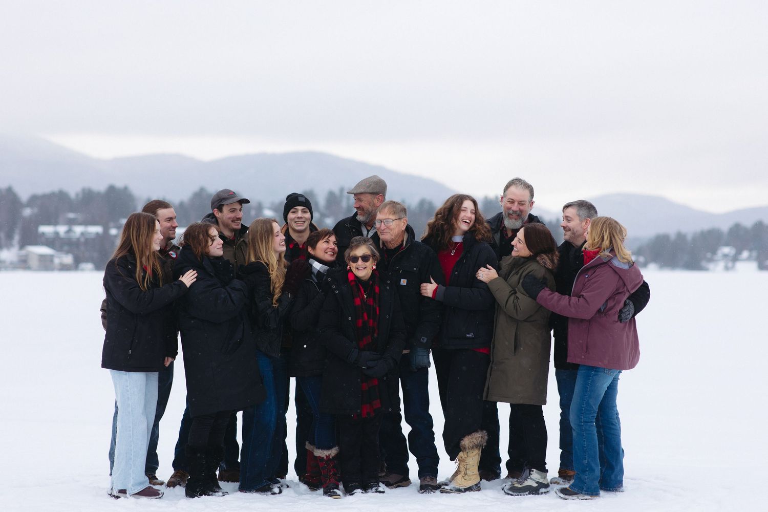 Large group poses together on a snow-covered landscape with mountains in the background.