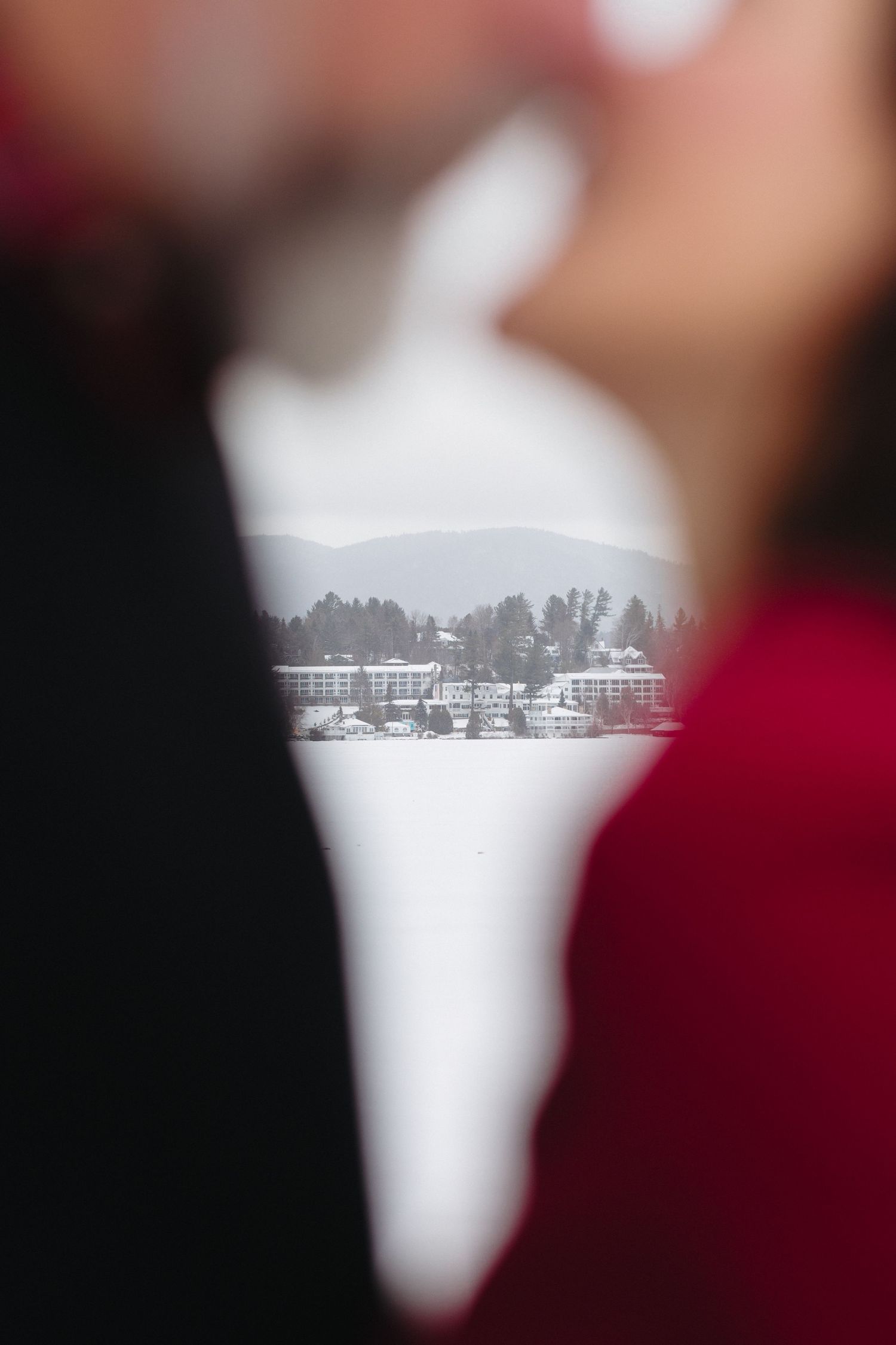 A creative framed winter landscape view of snow-covered buildings and trees through a heart-shaped opening.