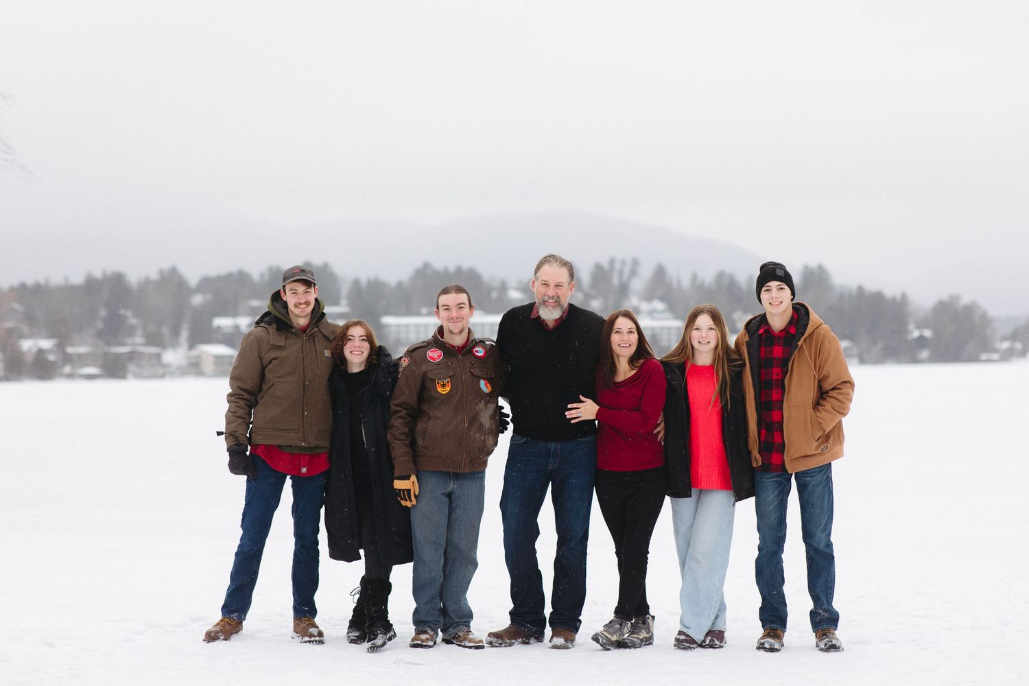 Group of people standing together in a snowy winter landscape wearing warm coats and jackets.