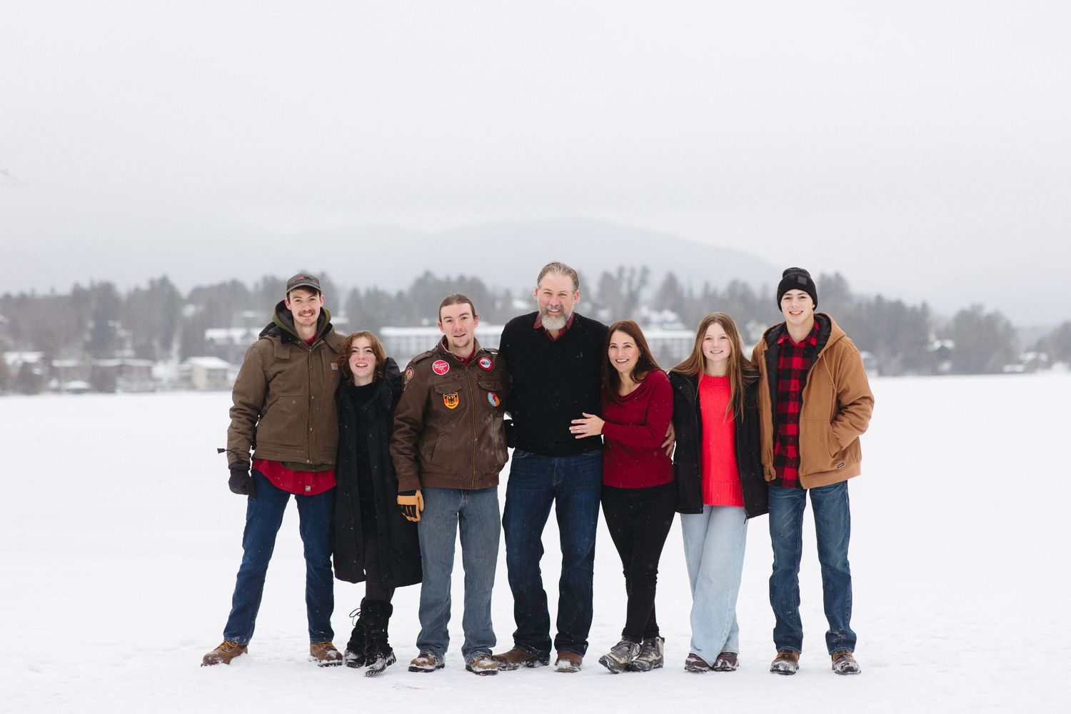 A group of people stand together in a snowy winter landscape wearing warm coats and winter attire.
