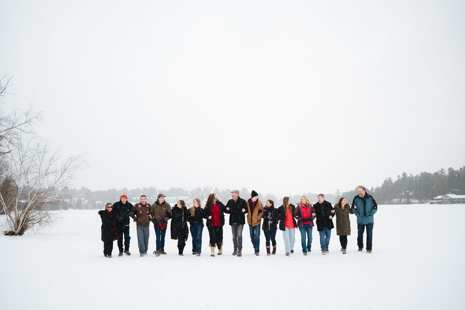 A large group stands in a line against a snowy white winter landscape.