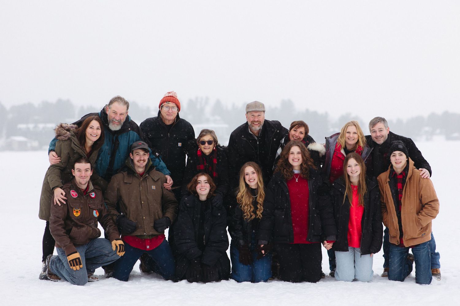 A group of people posing together in winter snow wearing warm coats and winter attire.