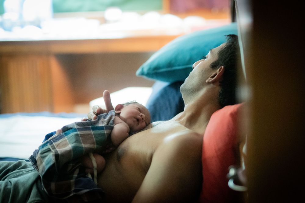New father resting with baby on his chest during skin to skin bonding