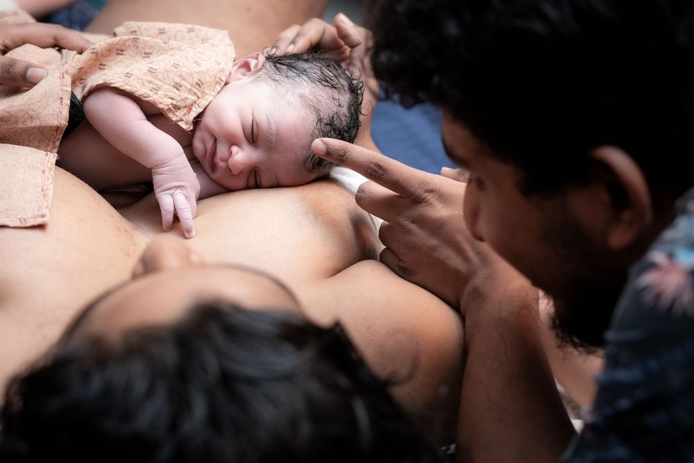 Father touching baby’s head during first skin to skin moment after birth
