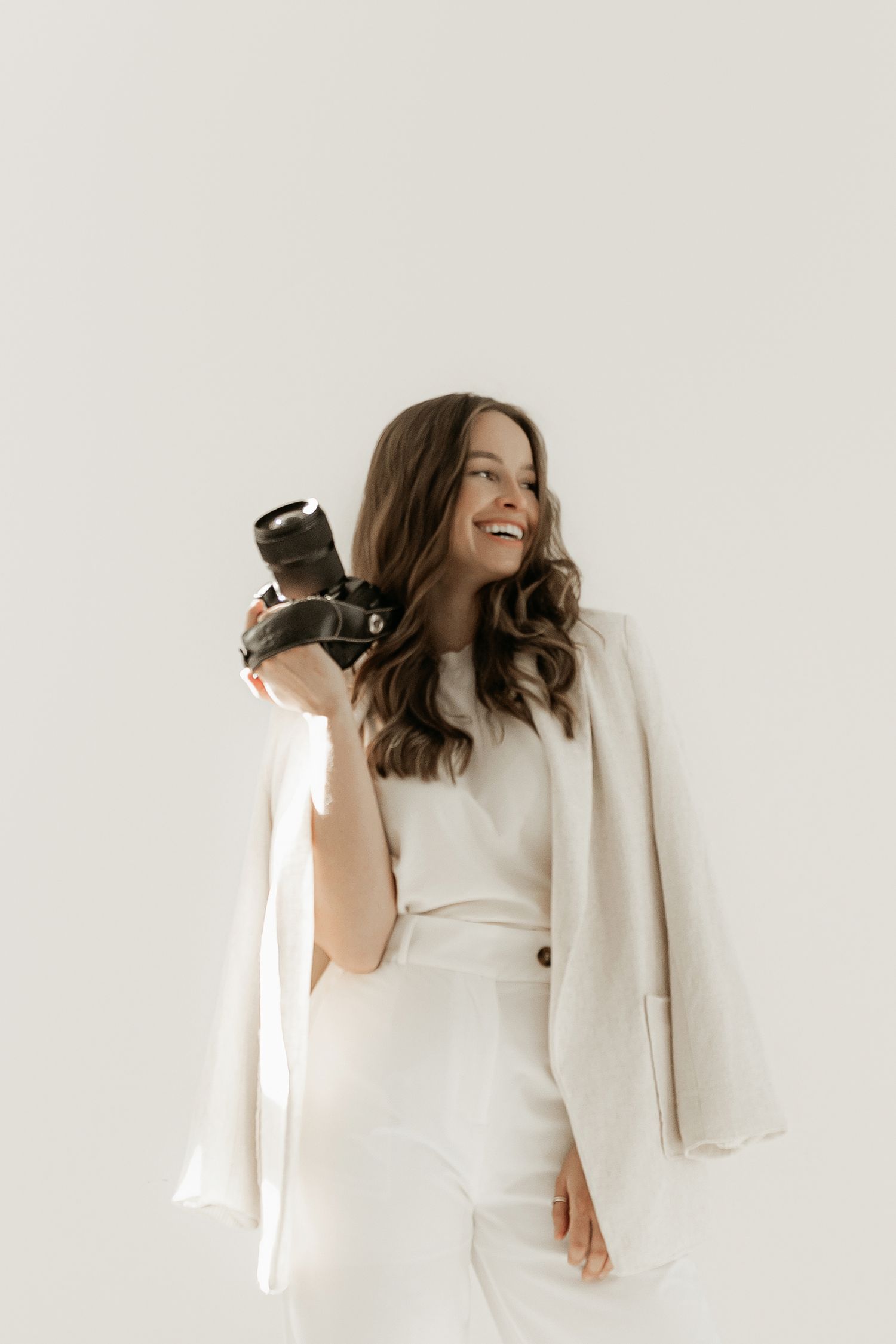 A person in a flowy white top and brown pants dances gracefully against a light background in a three-panel photo series.