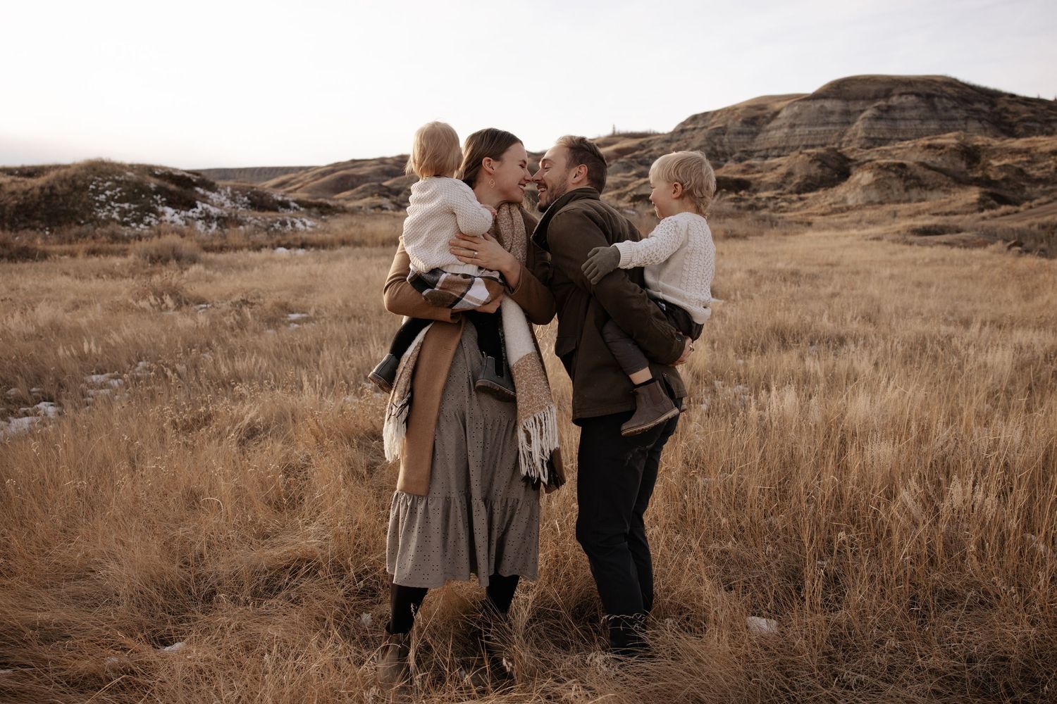 A series of sepia-toned photographs showing people embracing in a rustic outdoor setting with brown grass and rocks.