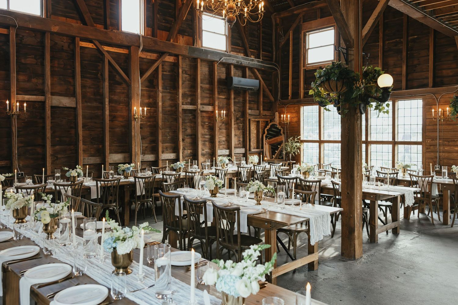 Wedding ceremony setup with white chairs on a lush green lawn facing a historic stone church under cloudy skies.