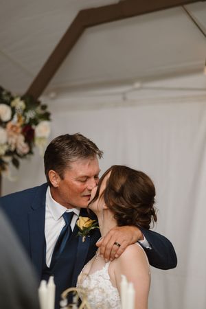 Intimate wedding reception moment under white tent with floral decorations.