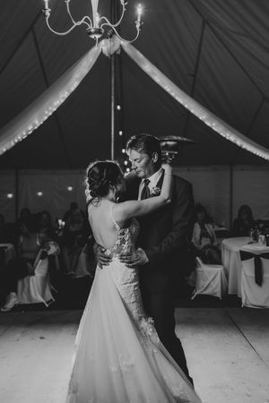 Wedding reception first dance under tent with romantic chandelier lighting.
