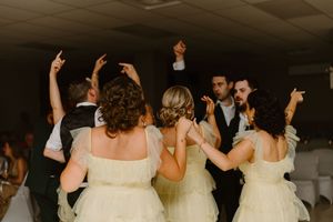 Wedding guests dancing together on the dance floor at a celebration with people wearing white formal attire.