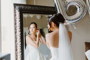Elegant bridal wedding preparation portraits in white gown with dramatic lighting in ornate vintage interior setting.