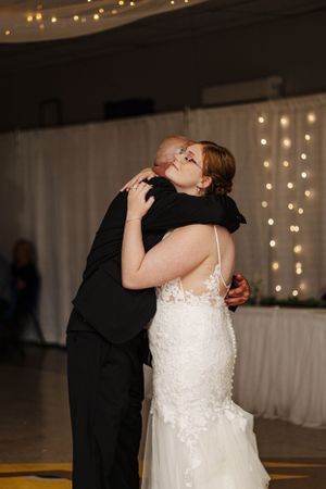 Tender moment during wedding reception dance with string lights in background.