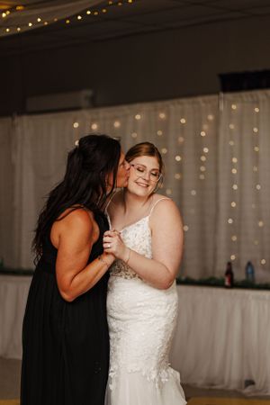 Emotional dance between bride and loved one at wedding reception with twinkle light backdrop.