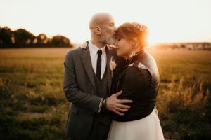 Tender embrace between couple in formal wear during golden sunset.