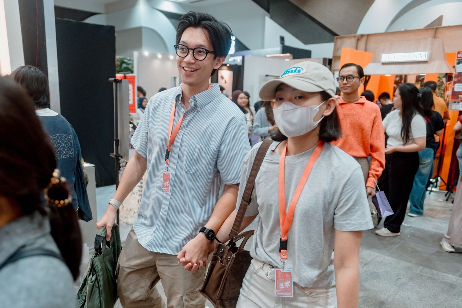 Conference attendees in gray and orange lanyards interact during a networking event at a tech convention.