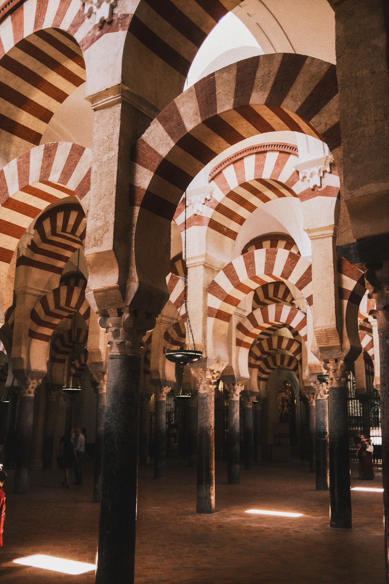 Interior of Mezquita-Catedral de Córdoba featuring iconic red and white striped arches and ornate columns.