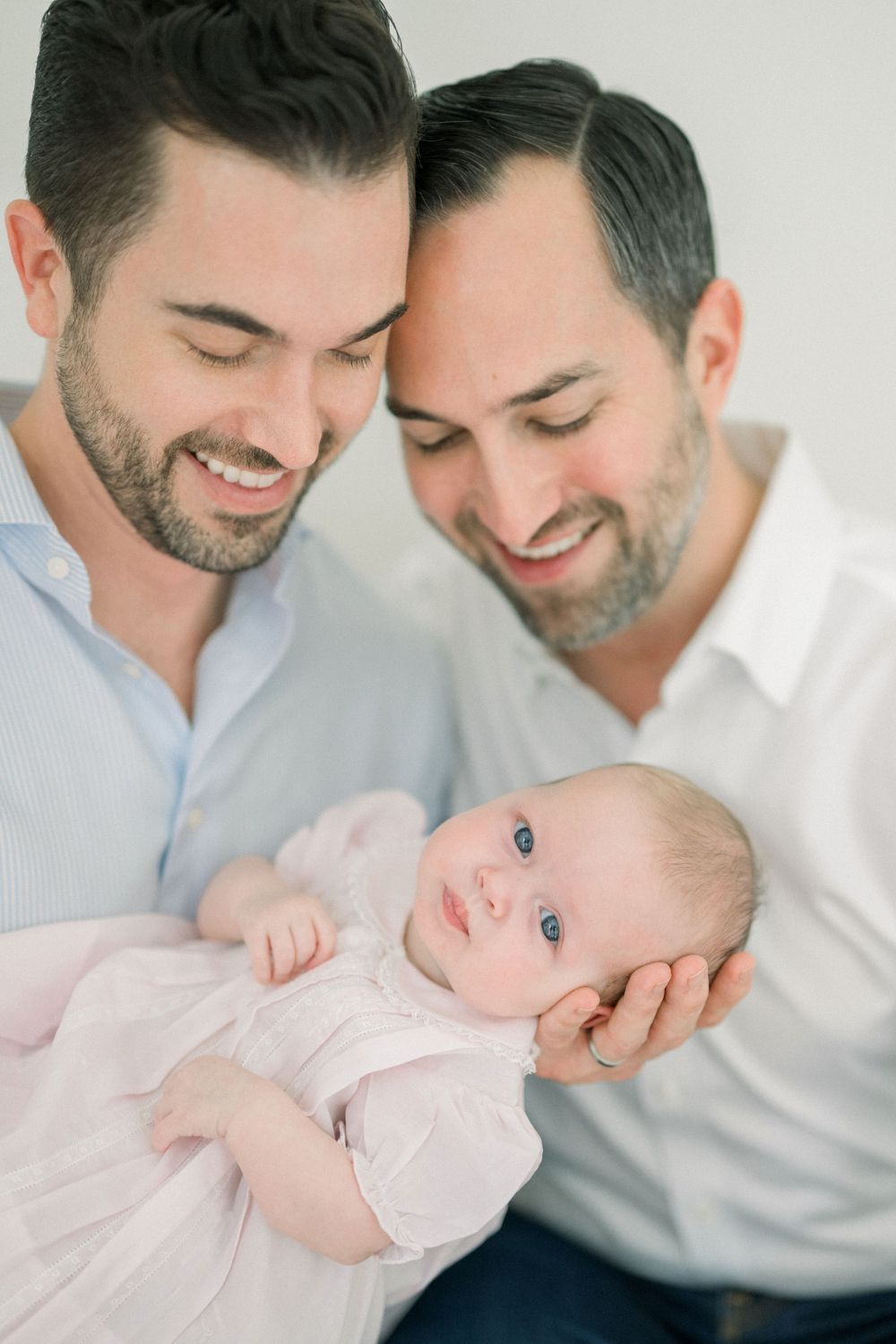 two dads smiling at their baby at a newborn session in washington dc