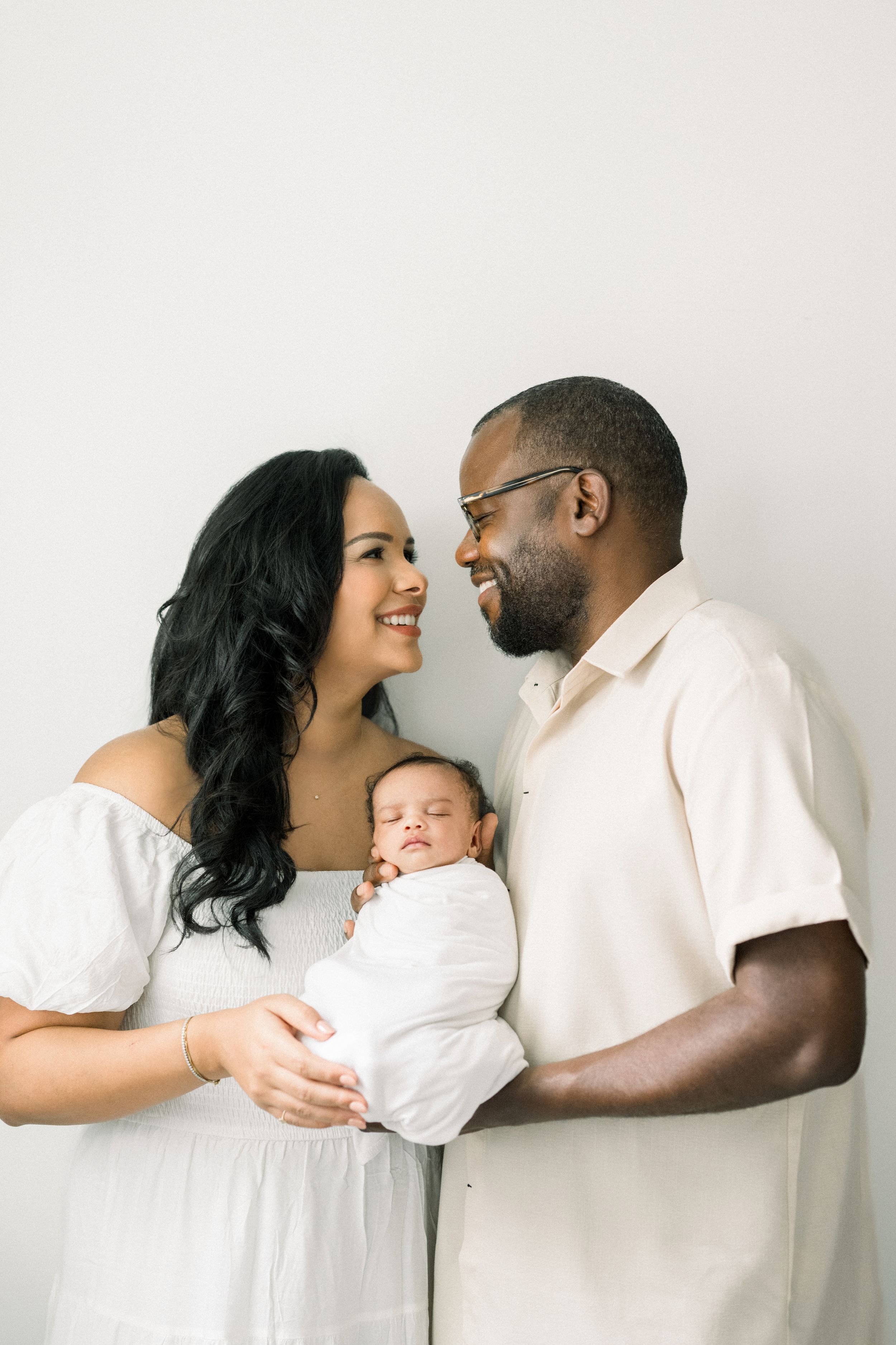 a couple holding their baby smiling at each other taken at an in-home newborn session in washington dc
