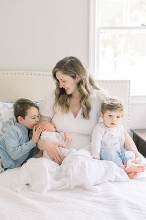 mom sitting on bed with her babies at a newborn session in arlington virginia