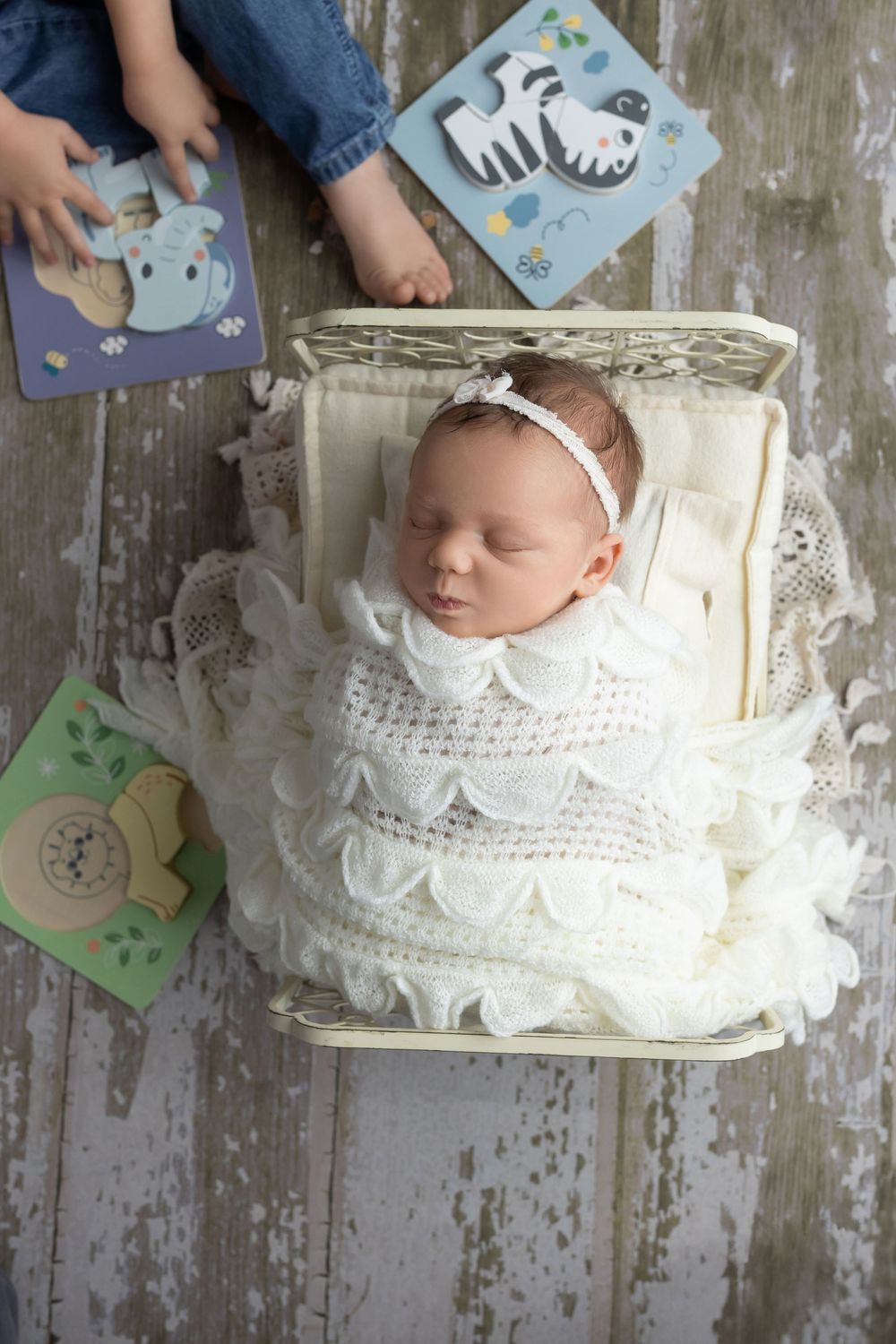 Older child doing puzzles near newborn baby, taken by Jen Knightstep, Photographer