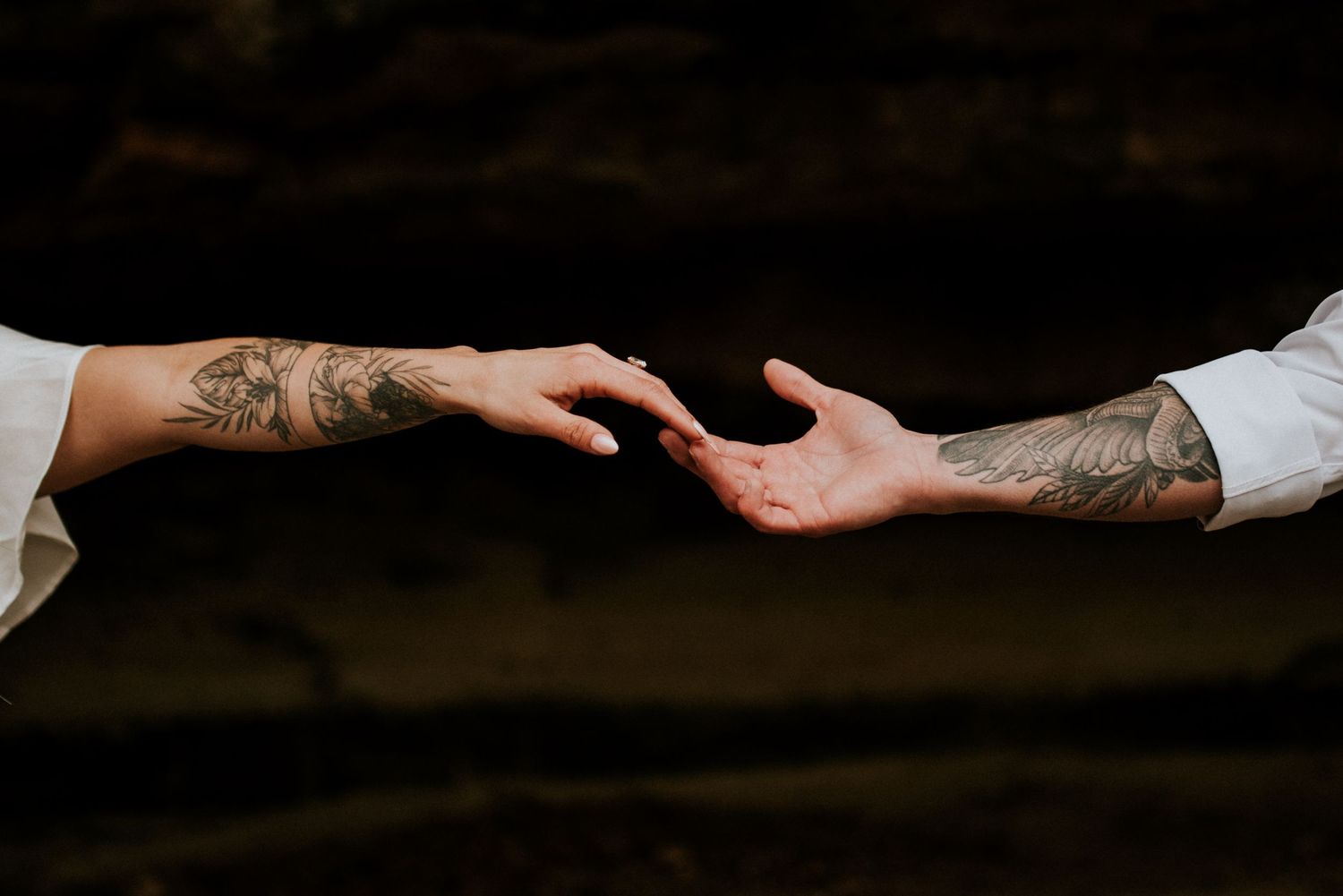Newly married hands showing off tattoos and rings as they reach for each other after their elopement ceremony in Nashville, Tennessee.