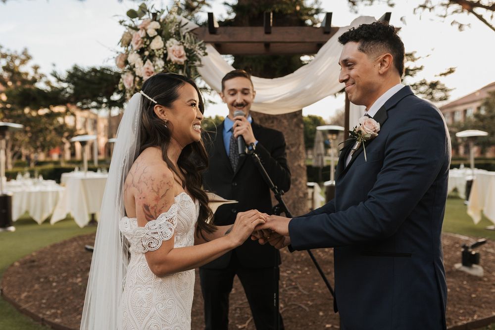 A couple smiles at each other during their outdoor wedding celebration at Stone Brewing Liberty Station in San Diego.