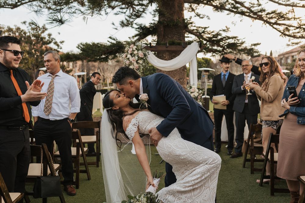 A couple shares a dip kiss at the end of their wedding ceremony at Stone Brewing Liberty Station in San Diego.