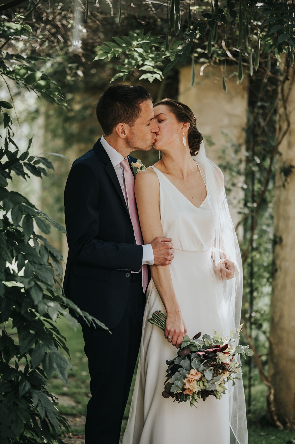 Romantic wedding moment captured in a lush green garden setting.