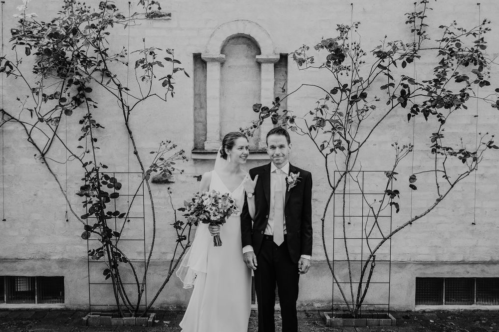 Black and white wedding portrait against a brick wall with climbing vines.