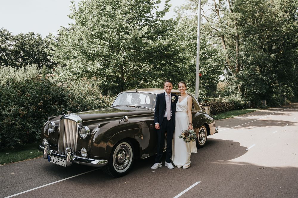 Classic vintage car parked outside on a sunny day at an elegant wedding venue.