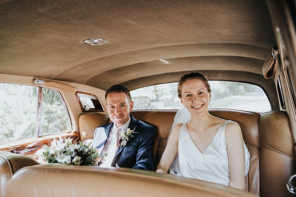 Interior view of a classic car with beige leather seats and vintage dashboard.