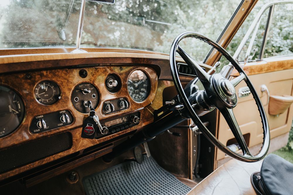 Interior dashboard view of a vintage luxury car showing wooden panels and classic gauges.
