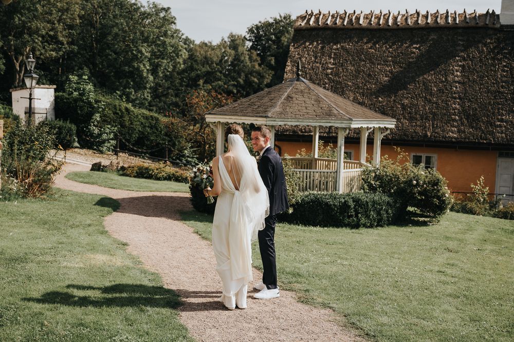 Scenic outdoor wedding venue path surrounded by lush greenery and gardens on a sunny day.