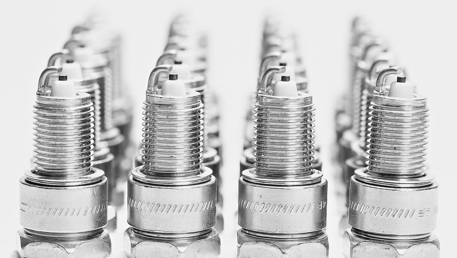 Row of identical silver spark plugs lined up in perfect formation.