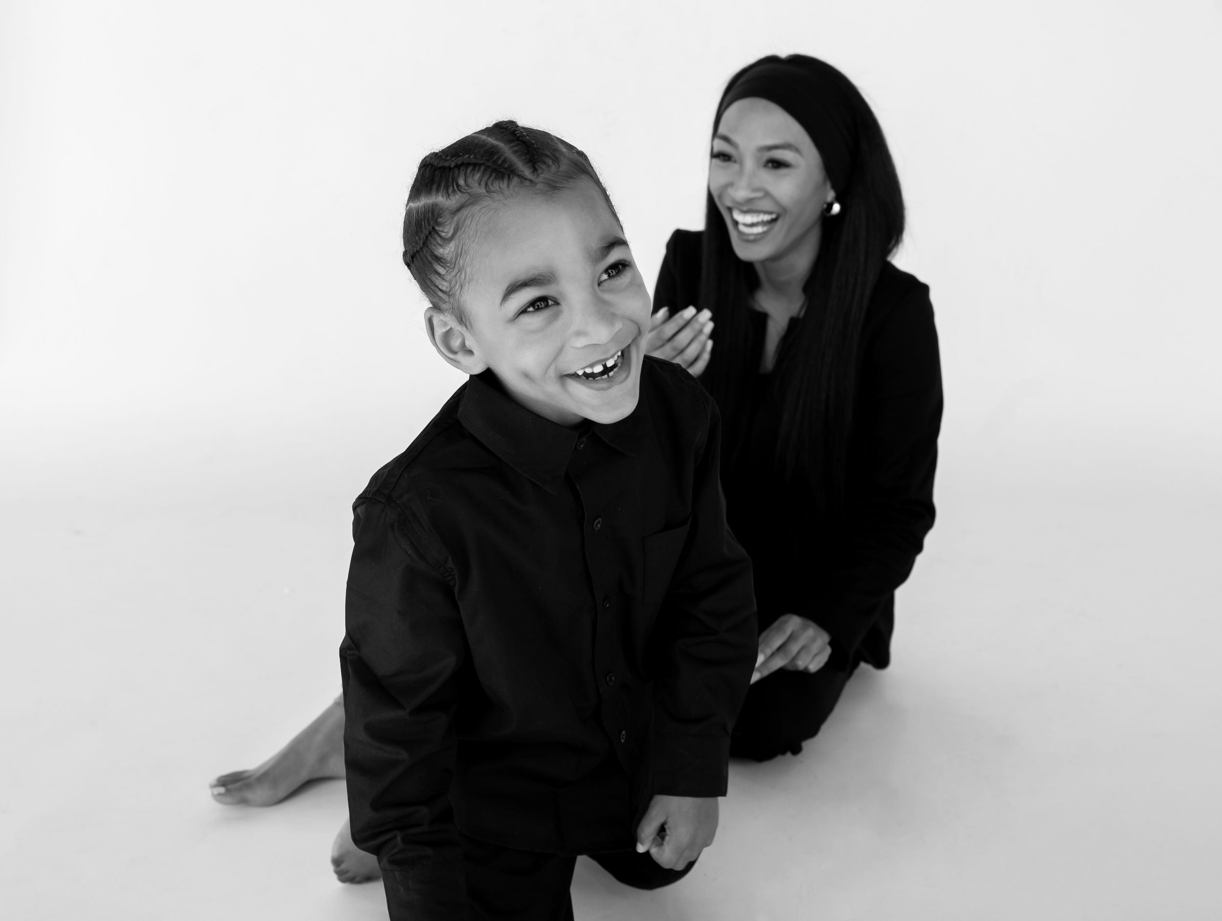 A series of four black and white photos showing joyful laughter and interaction between two people against a white backdrop.