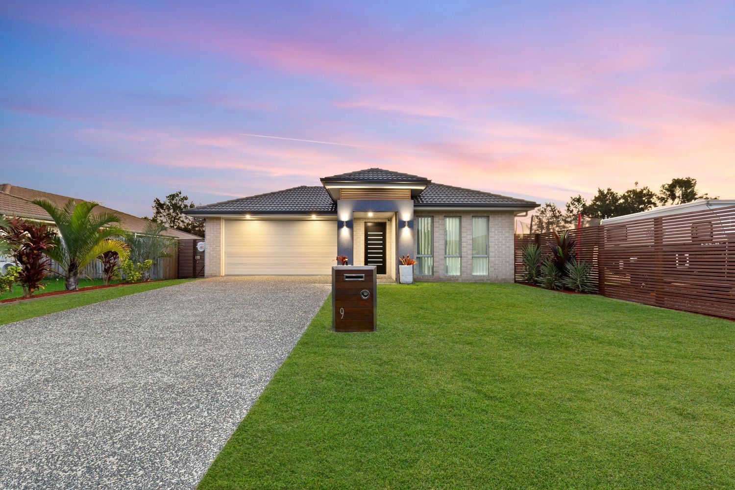 Modern Australian home with double garage, gravel driveway and manicured lawn at sunset.