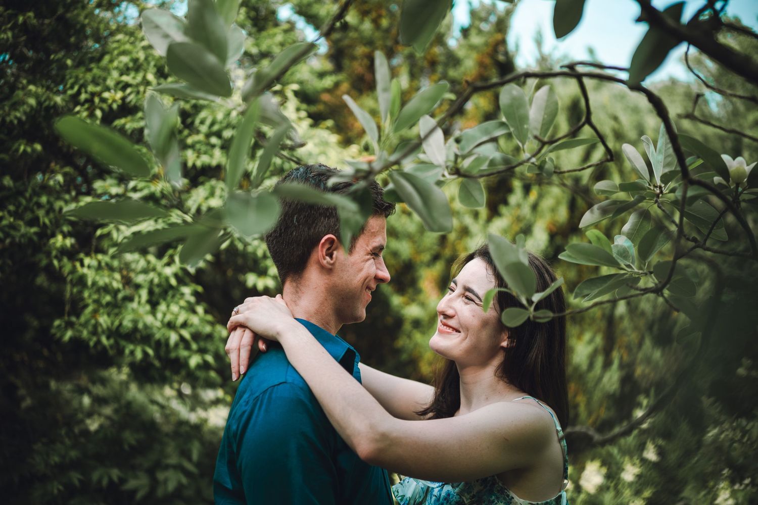 A romantic couple embraces while surrounded by lush green foliage at Brookside Gardens in Potomac, MD.