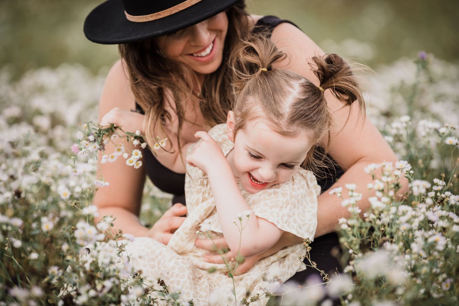 A joyful moment shared between two people in a field of white wildflowers on a warm summer day.