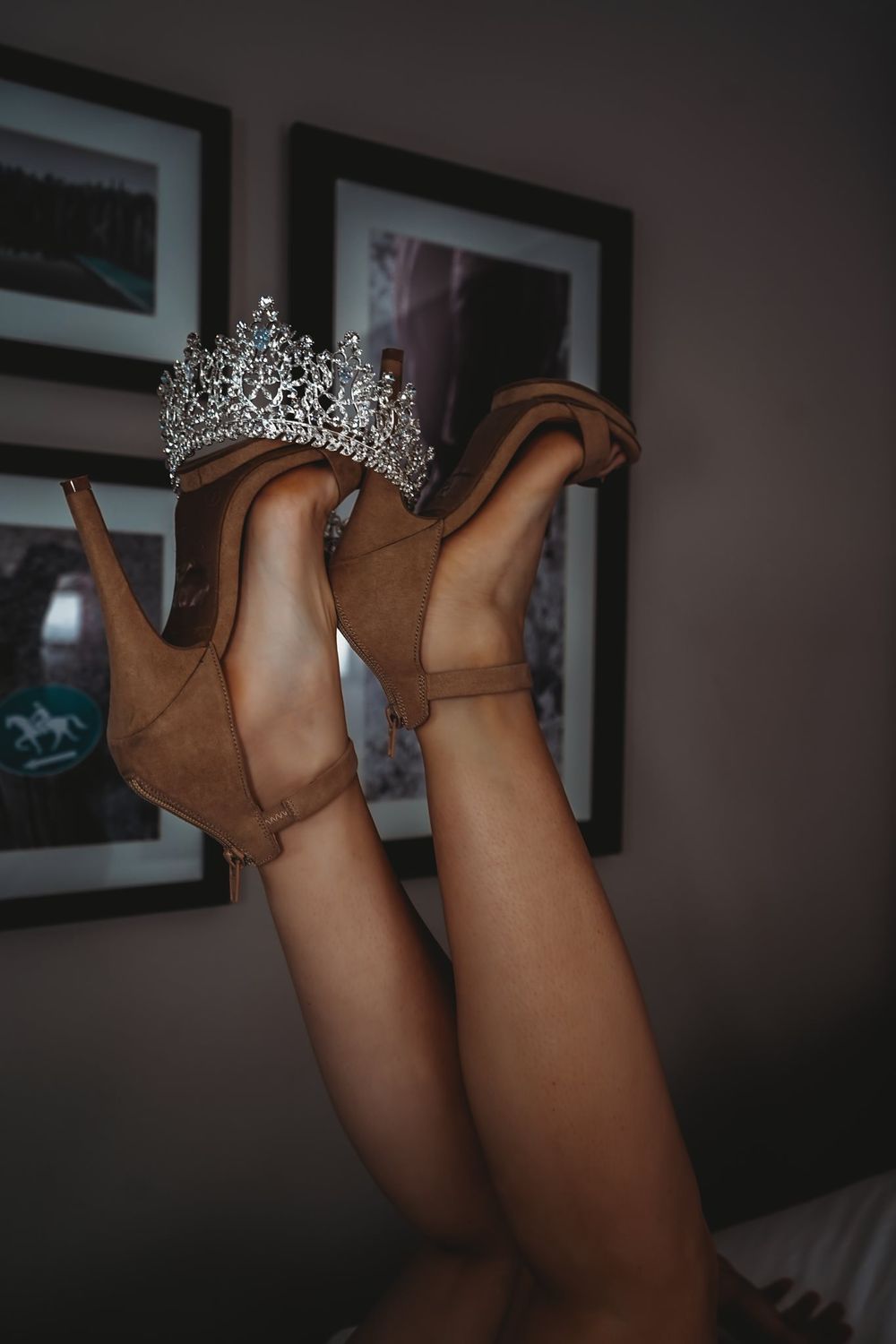 Brown ankle boots with sparkly tiara crown positioned against dark background.