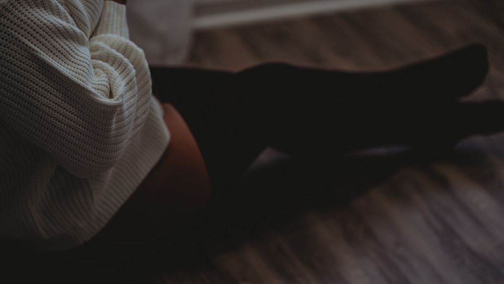 Artistic dark low-light photo of person lying on hardwood floor.