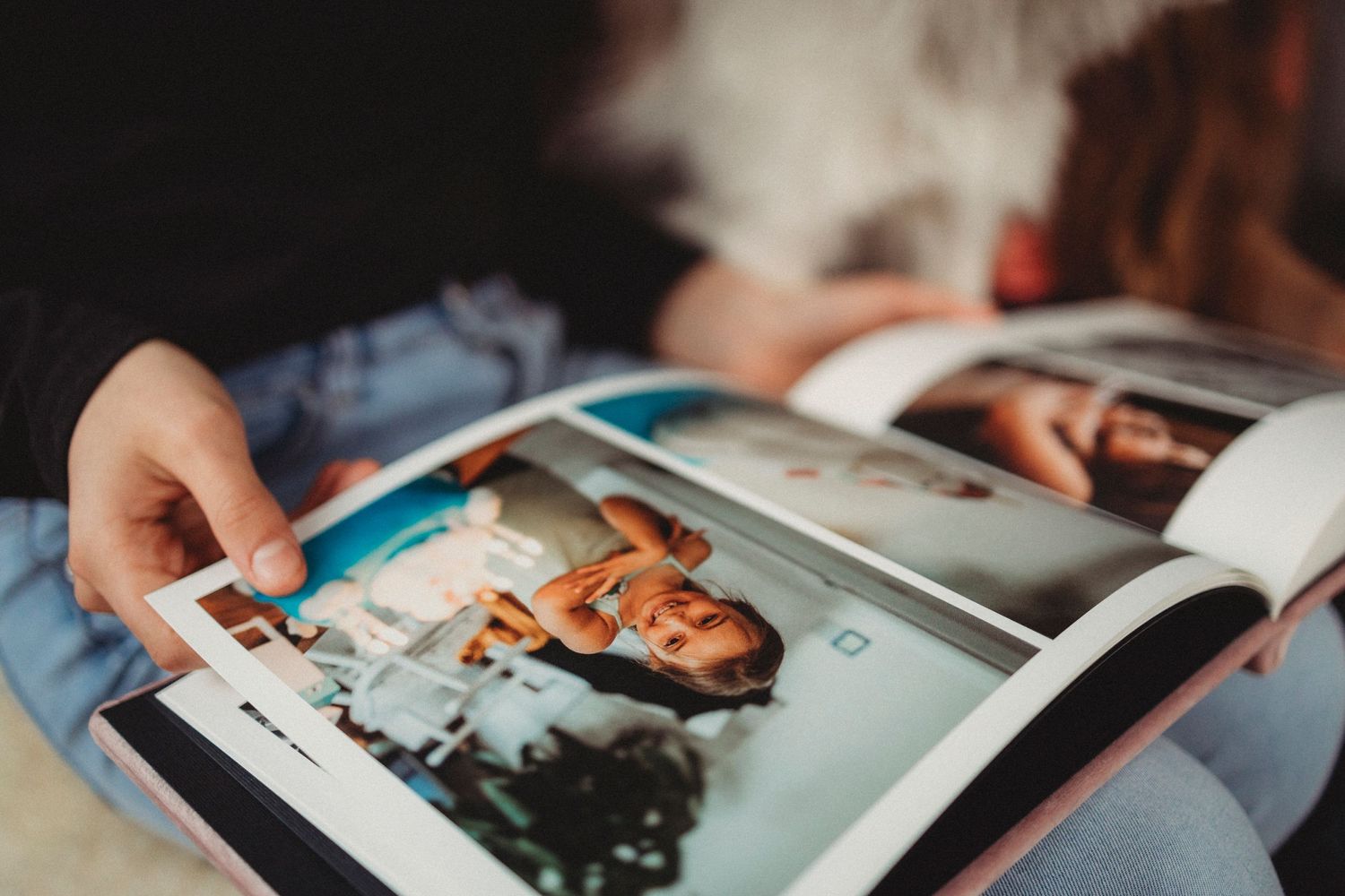 Person flipping through a photo album with photographs visible on glossy pages.