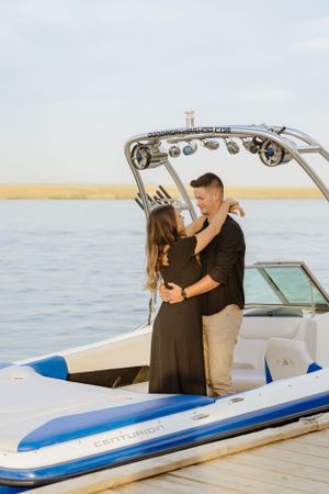Romantic couple embracing on a boat dock during golden hour.